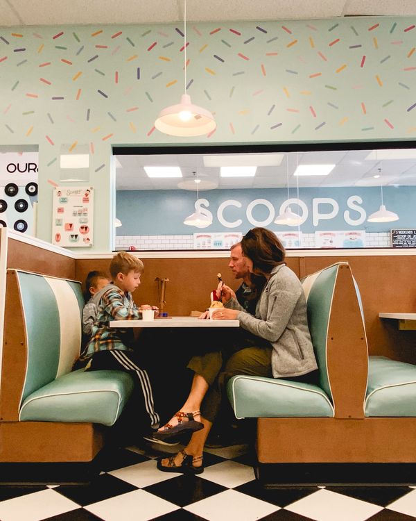 A woman and a boy sharing treats in a booth at a retro ice cream shop
