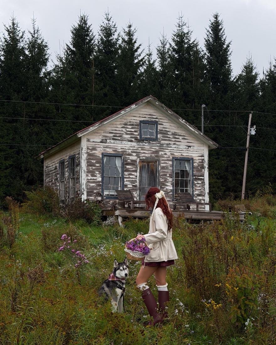 A traveler with a husky and a basket of wildflowers beside a weathered cabin