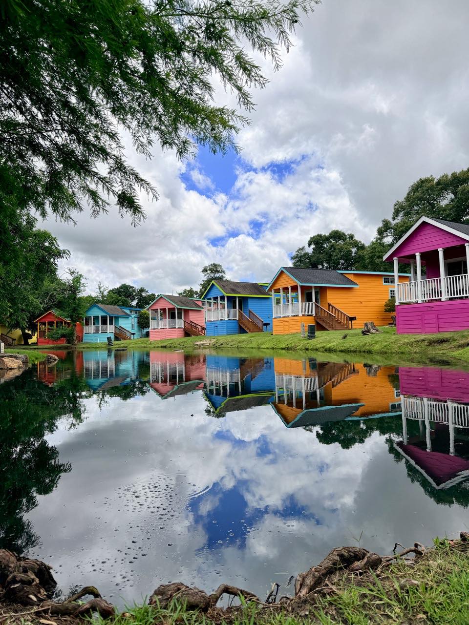 A row of brightly painted resort cottages reflected in a still pond